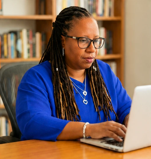 Davina Wright-Lyons working at a laptop, from her Rising Resilience business one-pager